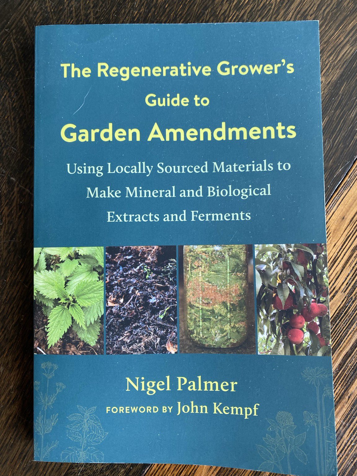 We see a green book cover on a wooden table. We see exciting words such as garden amendments, extracts, ferments